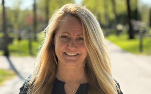 Lisa står med utsläppt långt blont hår på en grusväg med träd i bakgrunden