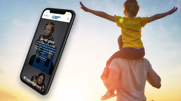 En smartphone som visar en webbsida från Barncancerfonden. Bakgrunden är en man som bär ett barn på sina axlar och går mot en vacker soluppgång.