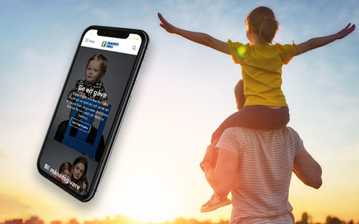En smartphone som visar en webbsida från Barncancerfonden. Bakgrunden är en man som bär ett barn på sina axlar och går mot en vacker soluppgång.