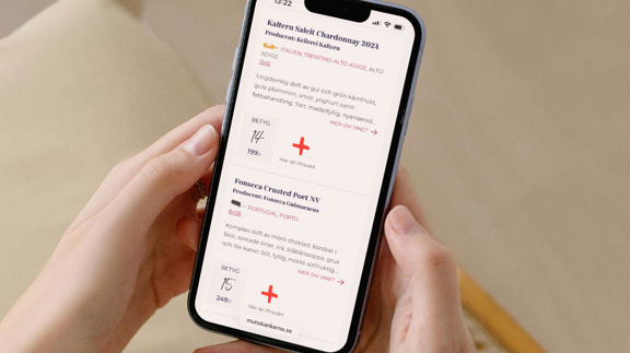 Mobiltelefon i händer som visar detaljerad vininformation och betyg på Munskänkarnas webbplats.