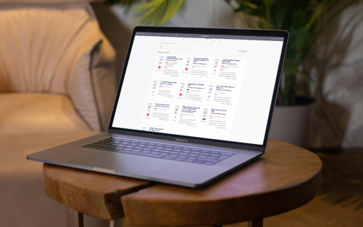 Laptop på ett runt träbord i vardagsrumsmiljö med Munskänkarnas webbplats öppen på skärmen.